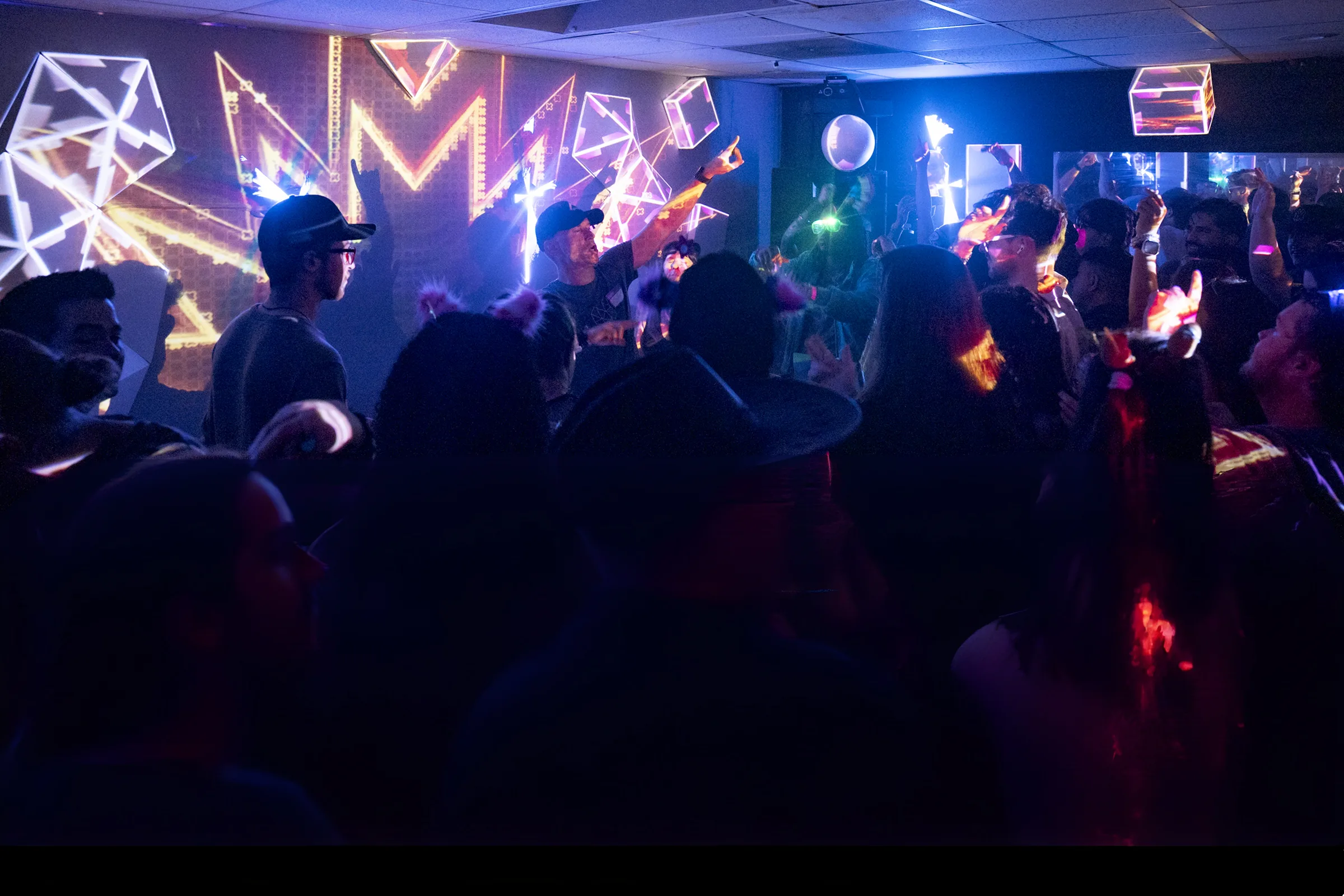 A silhouetted crowd dances under geometric light projections at a Lightclub event